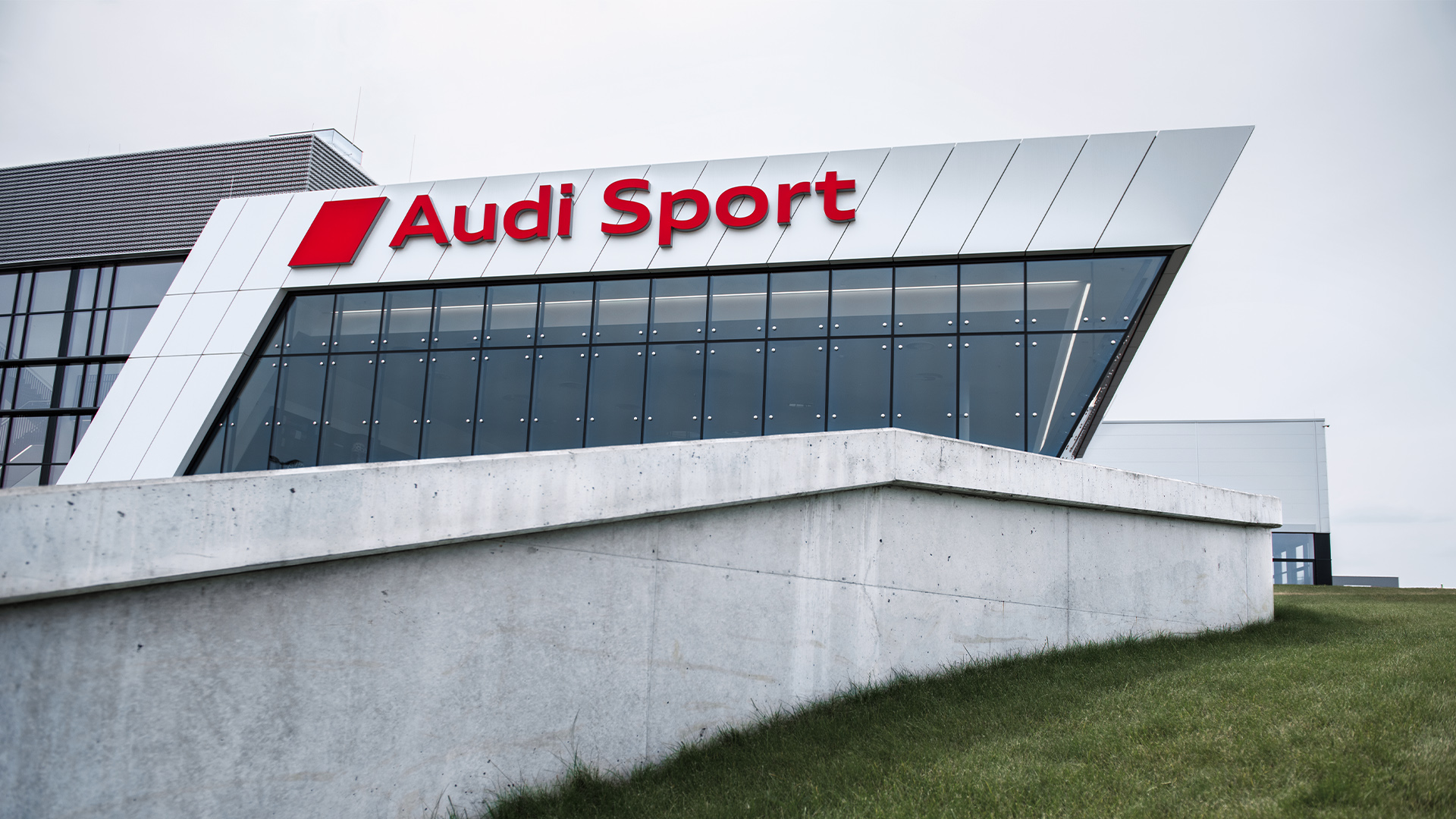 Za niewielkim murkiem widać budynek Audi Sport.
