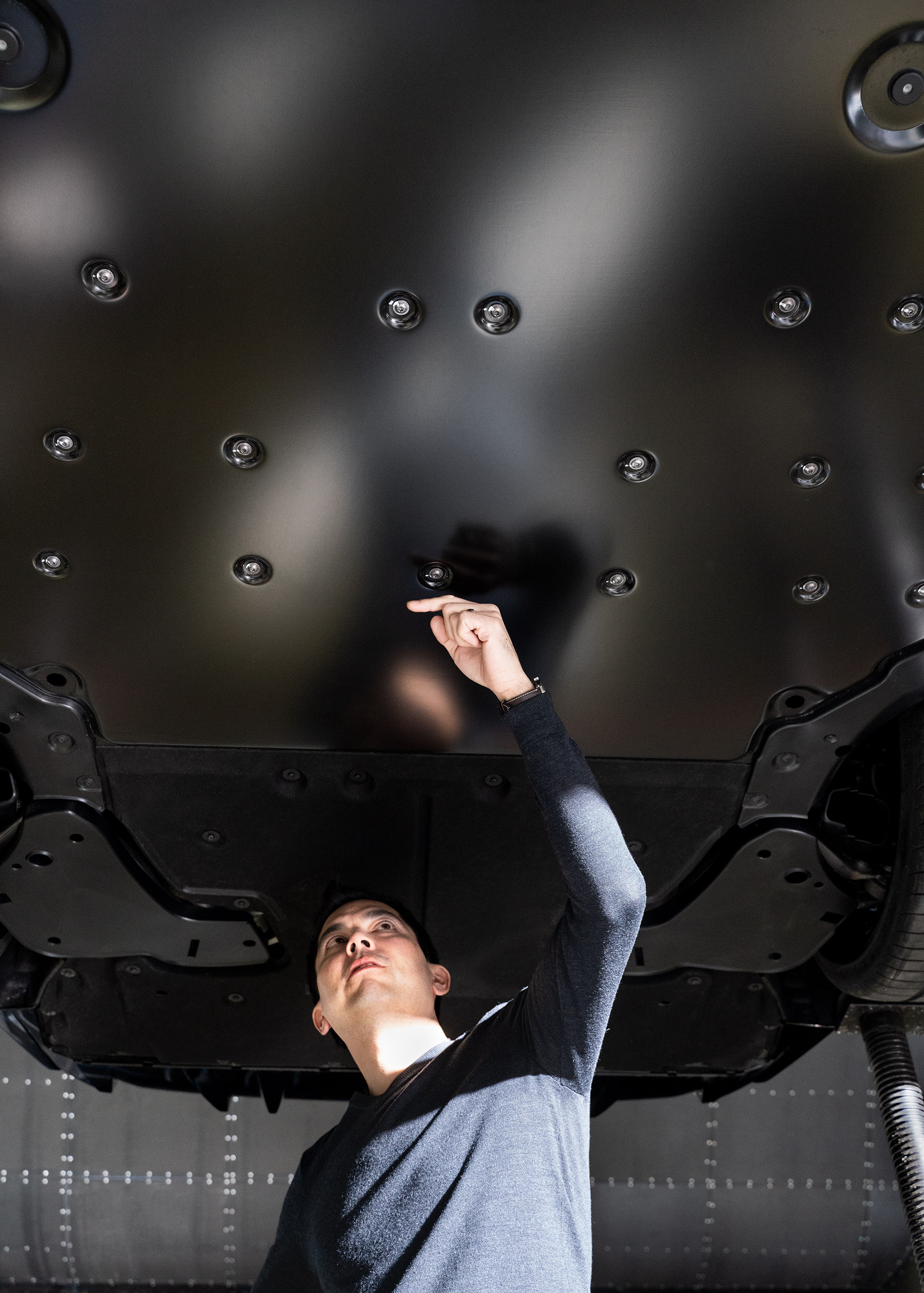 Doktor Kentaro Zens, aerodynamik odpowiedzialny za Audi RS e-tron GT, wskazuje na podwozie samochodu sportowego.