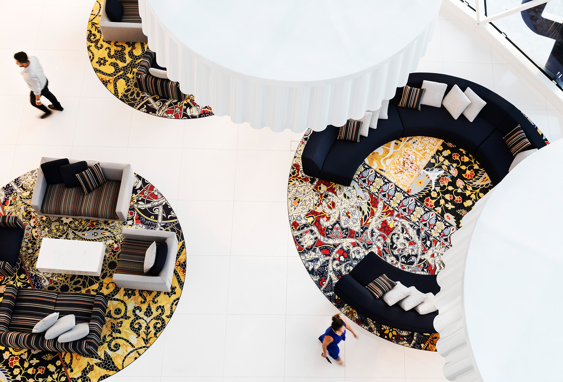  Widok z lotu ptaka na hotelowe lobby z okrągłymi, kolorowymi wyspami do siedzenia.