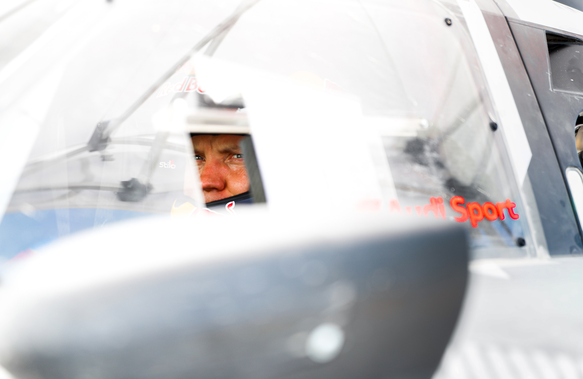 Zbliżenie twarzy Mattiasa Ekströma siedzącego za kierownicą swojego samochodu rajdowego.